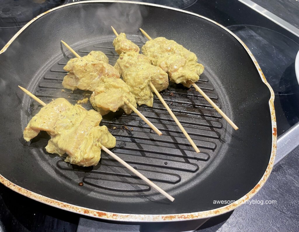 sticks with meat are being grilled on the pan